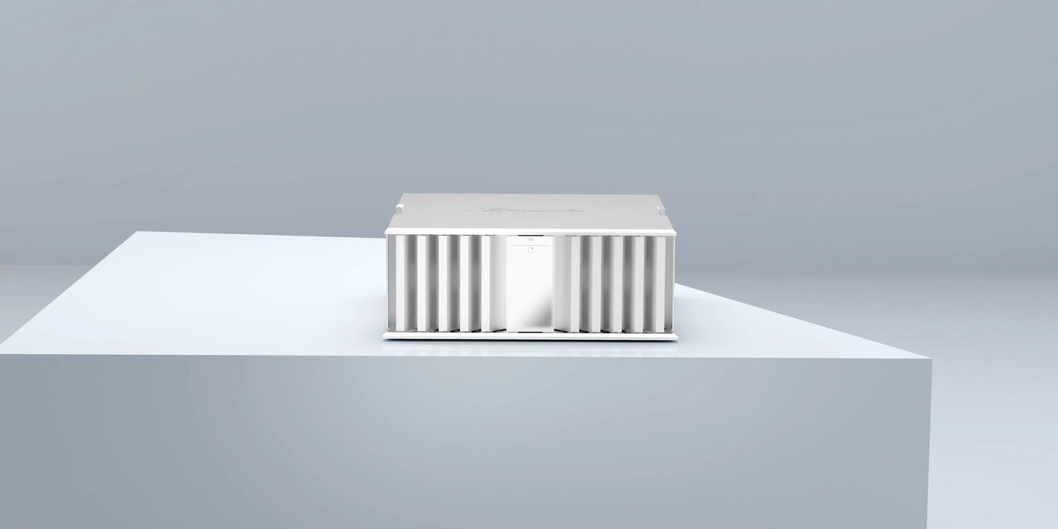 A silver Burmester 216 Top Line Power Amplifier on a gray table with a gray background - HiFi Centre.