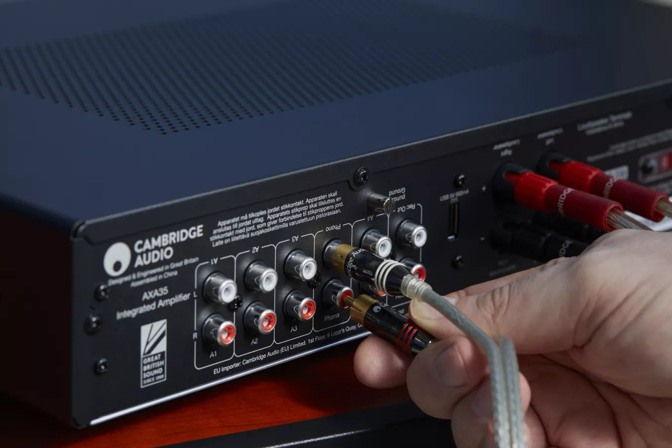 Person connecting audio cables to a Cambridge Audio AXA35 Integrated Amplifier.
