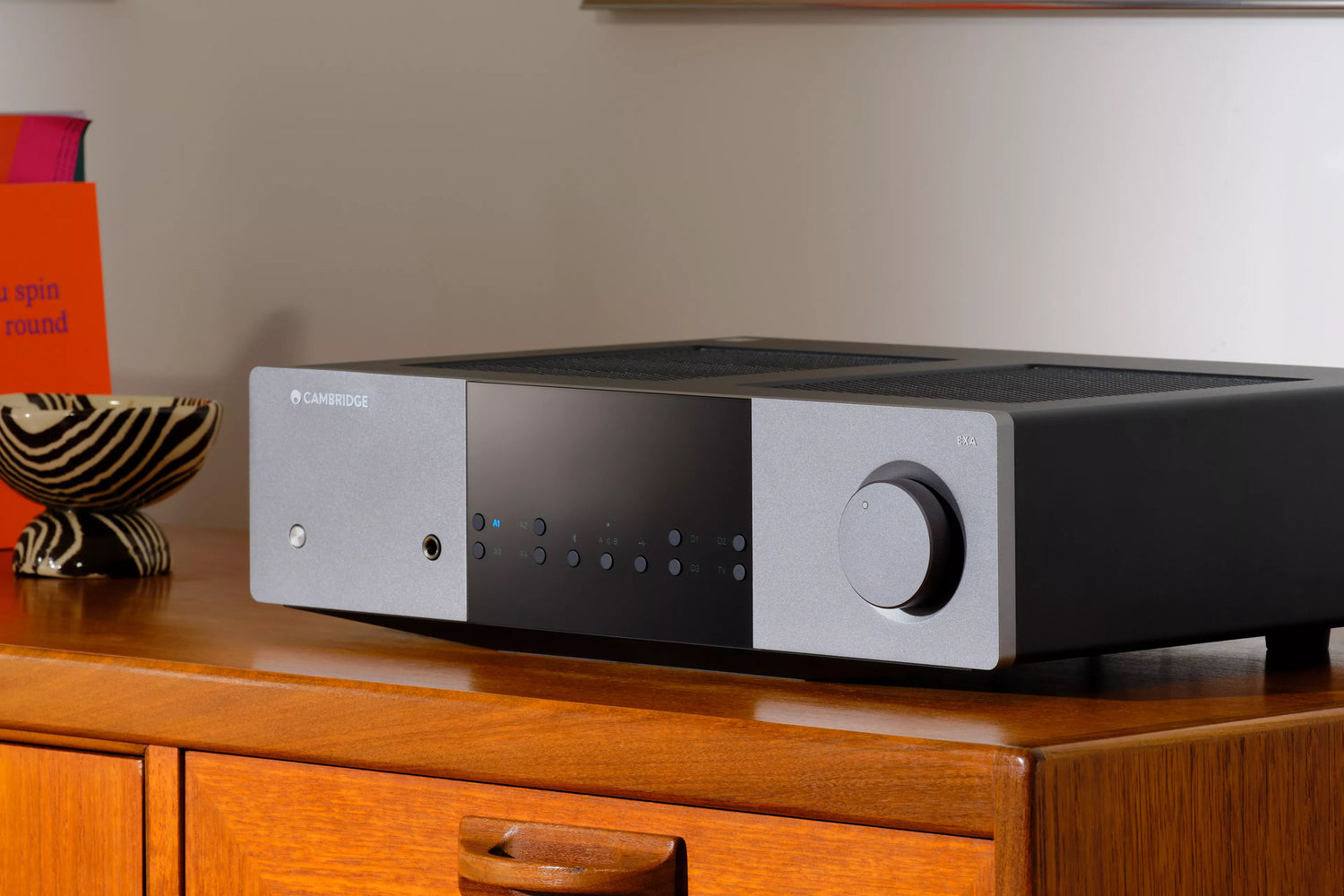Cambridge Audio EXA100 Integrated Amplifier on a wooden surface in a modern living room.