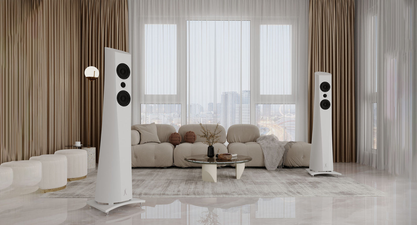 An Estelon white Aura Floor Standing Speakers with a white front and black base, featuring a minimalist design in a modern living room.
