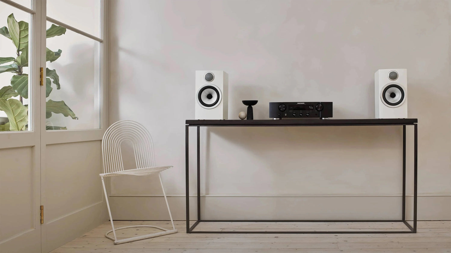 A pair of white B&W's 706 S3 Bookshelf Speakers on a table next to hifi system in a modern music room.