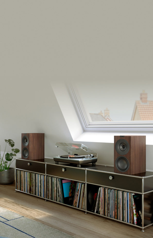 A pair of walnut KEF Q3 Meta Bookshelf Speakers in a modern music room.