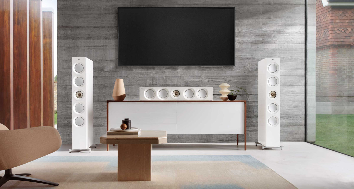 Modern living room with white floor-standing KEF Reference 4 Meta
speakers, a television, and decorative items.