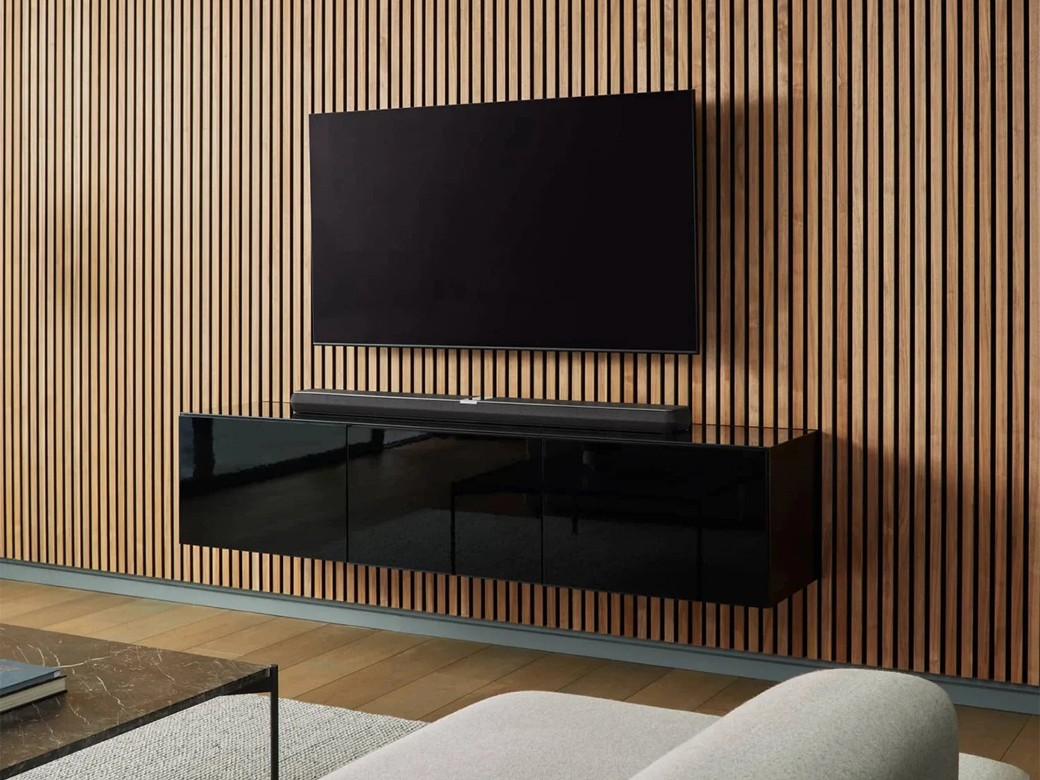 A modern living room with wood panelling on a TV wall featuring setup with a B&W Panorama 3 Sound Bar.