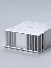 A side side of a silver Burmester 218 Reference Line power amplifier with cooling fins and ports on a gray surface - HiFi Centre.