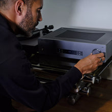 Person adjusting a large Cambridge Audio CXA81 MKII Integrated Amplifieron a wooden surface