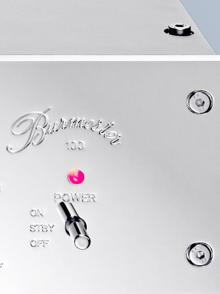 A detail of a logo of a silver Burmester 100 Top Line Phono Preamplifier with a classic chrome front panel, visible toggle switches, and a VU meter - HiFi Centre.