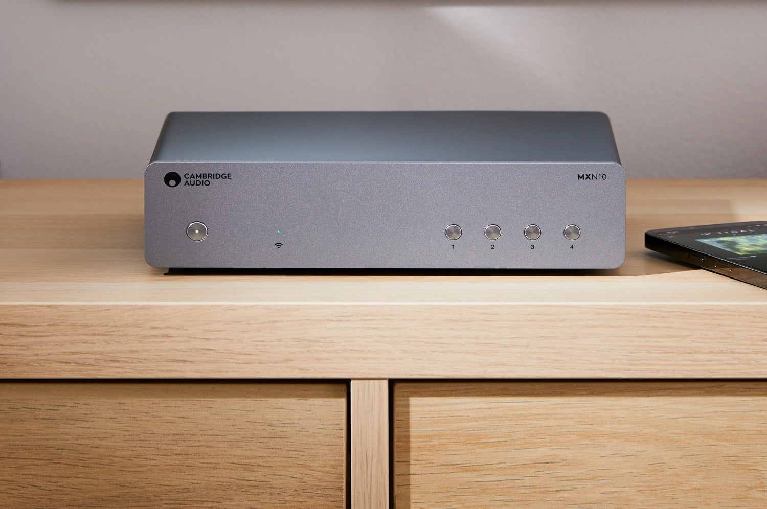 A Cambridge Audio MXN10 Compact Network Player on a TV bench in a modern living room.
