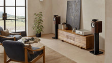 A pair of B&W 705 S3 Signature Bookshelf Speakers in datuk gloss finish in a modern living room.