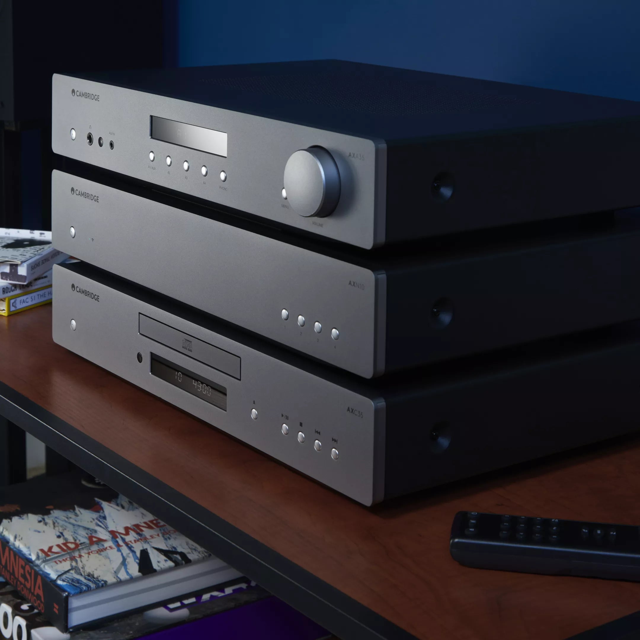 Stack of audio equipment on a shelf with a dark background featuring Cambridge Audio AXA35 Integrated Amplifier - HiFi Centre.