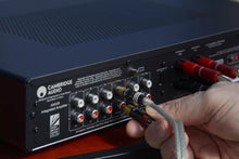 Person connecting audio cables to a Cambridge Audio AXA35 Integrated Amplifier.