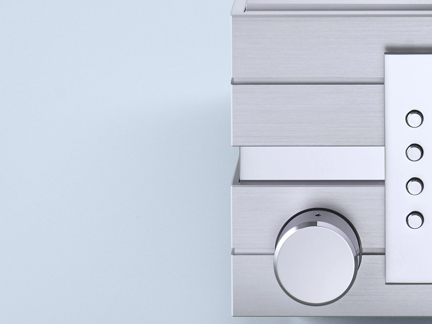 Close-up of a metallic control panel of a Burmester 111 Reference Line Music Center with circular dial and buttons on a light gray background.