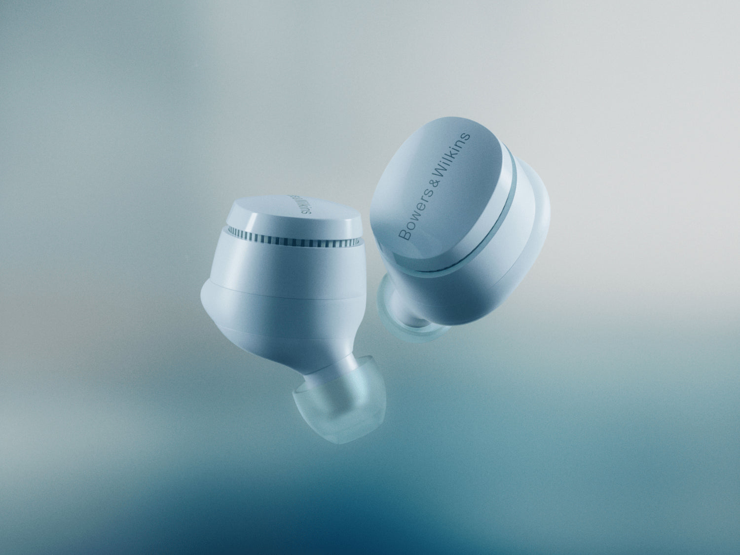 A closeup to a pair of B&W Pi6 True Wireless In-Ear Headphones in glacier blue color on a blurred background.