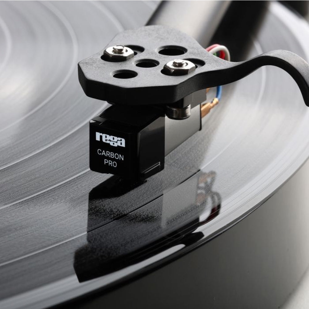 Rega Carbon Pro MM phono cartridge mounted on black tonearm over spinning vinyl record.