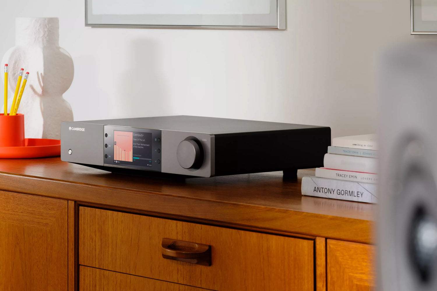 Cambridge Audio EXN100 Network Player on a wooden cabinet with books and a lamp in the background
