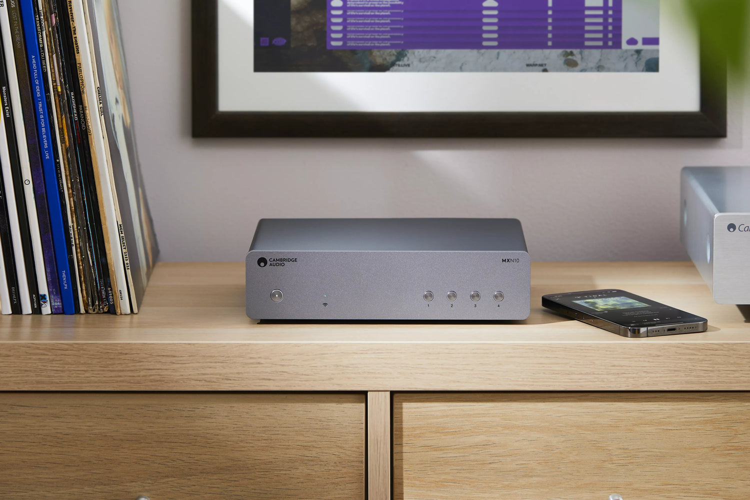 Cambridge Audio MXN10 Compact Network Player on a wooden surface with a television in the background.