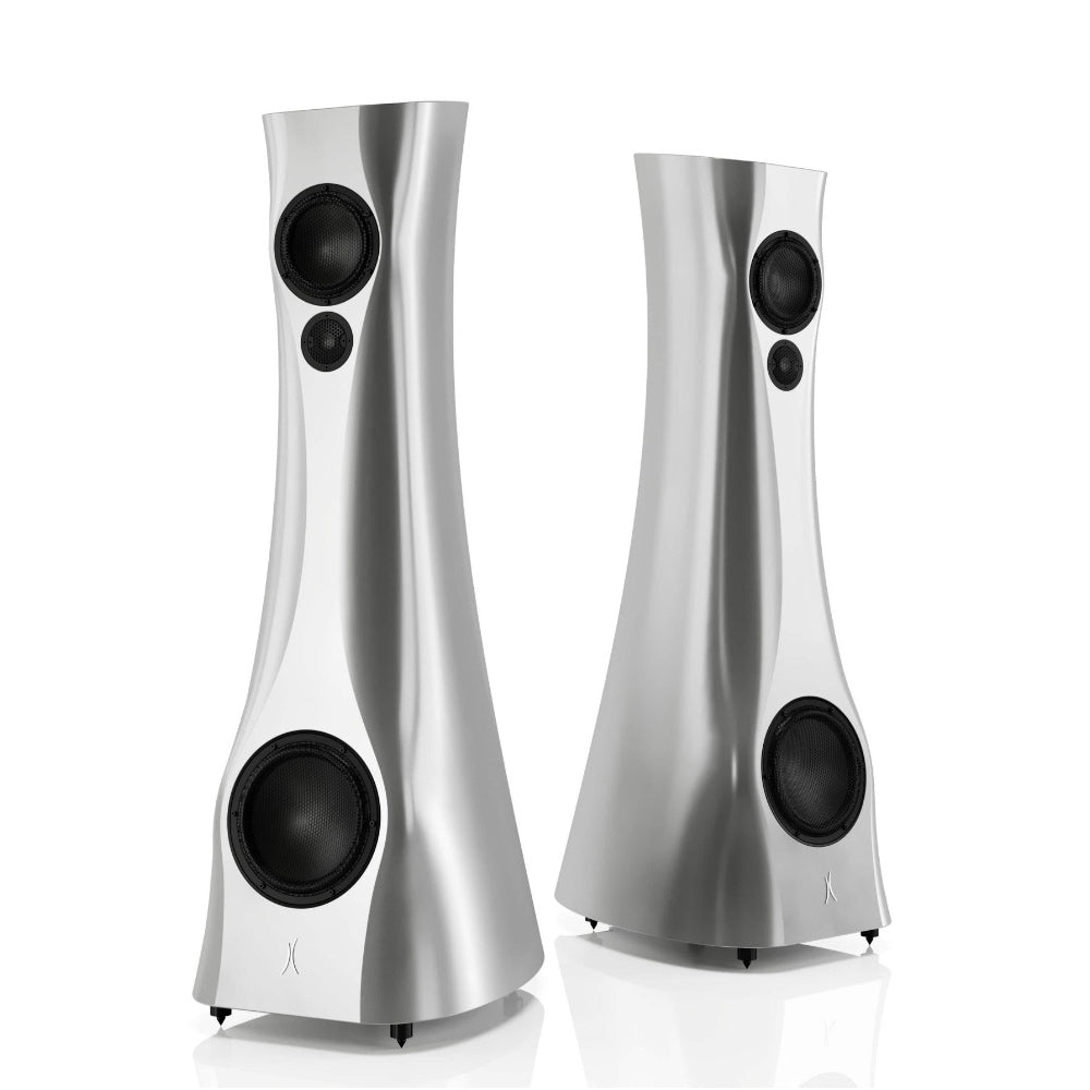A pair of Silver Pure Alu Matte Estelon XB MK II reference speakers with a curved-sculptural design, standing in a reflective environment.