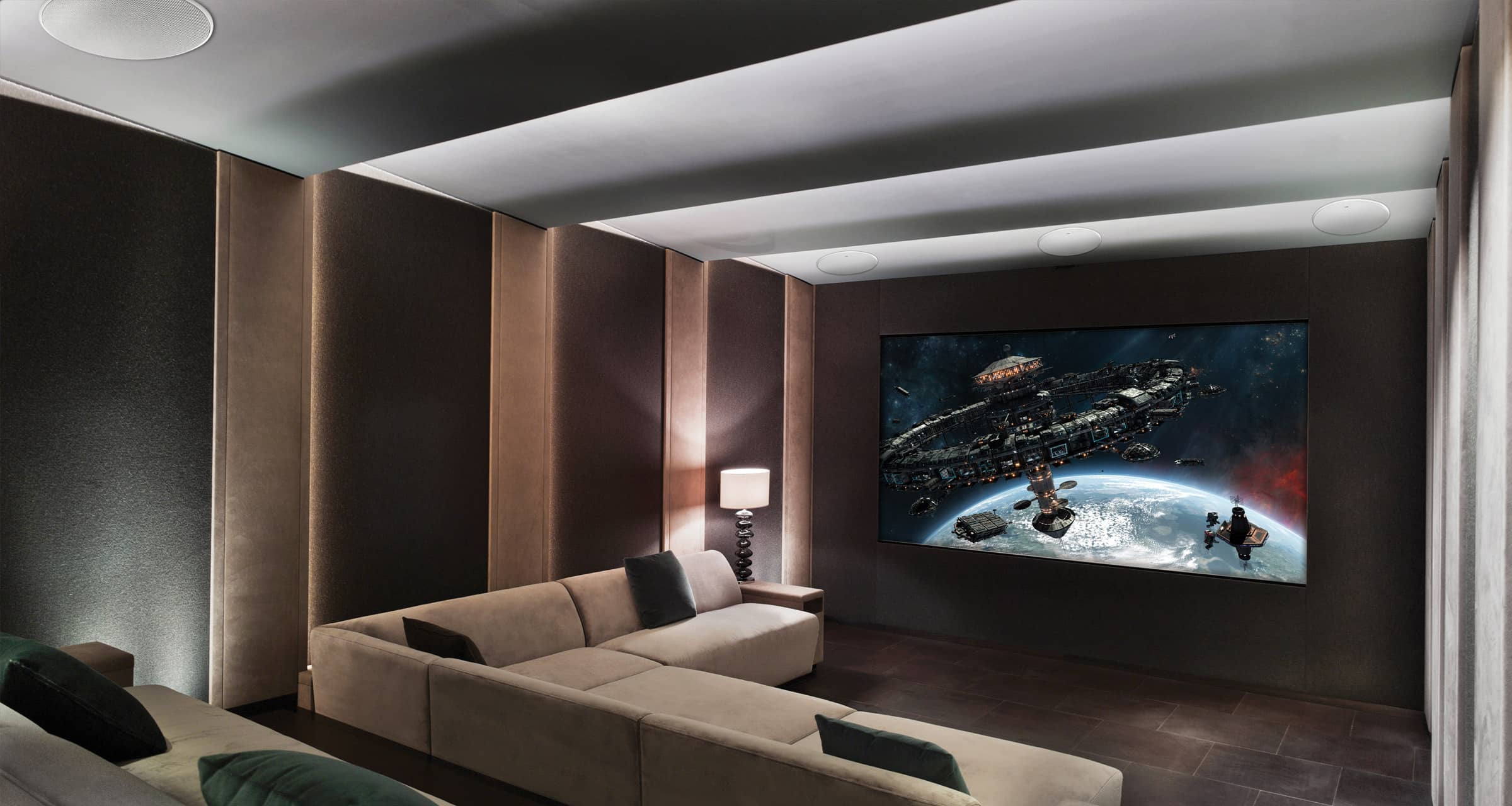 Modern home theater with a large screen displaying an outer space scene, with KEF Ci250RRM-THX Extreme In-Ceiling
speakers installed, surrounded by comfortable seating.