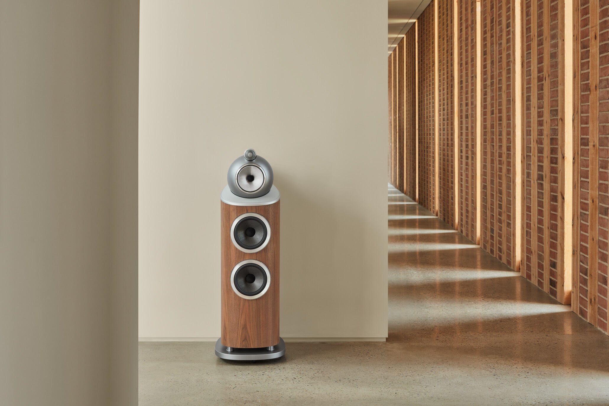A B&W 802 D4 Reference Speaker in walnut finish in a hallway.