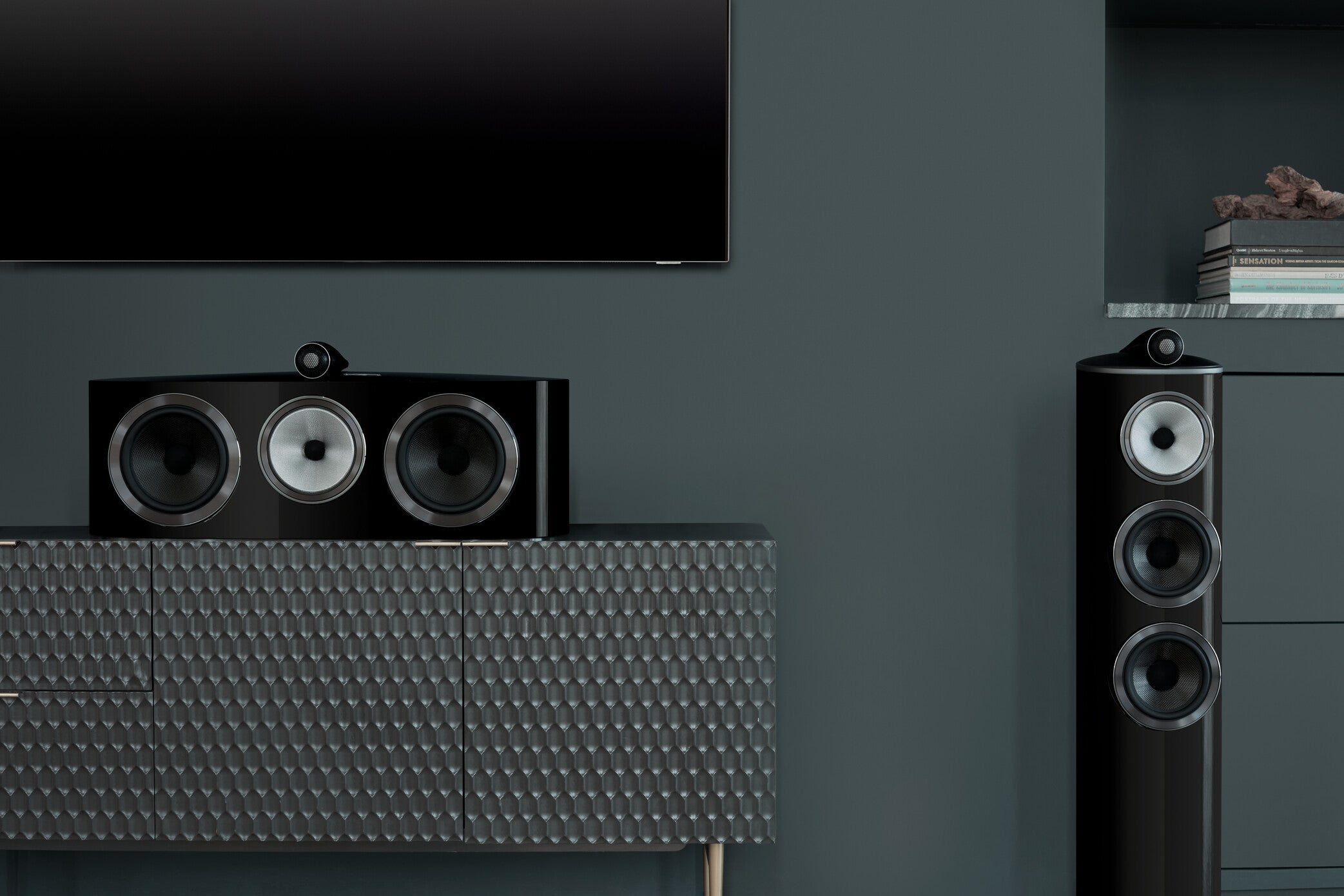 A closeup on a B&W 804 D4 Reference Speaker in gloss black finish and central speaker in a modern living room.