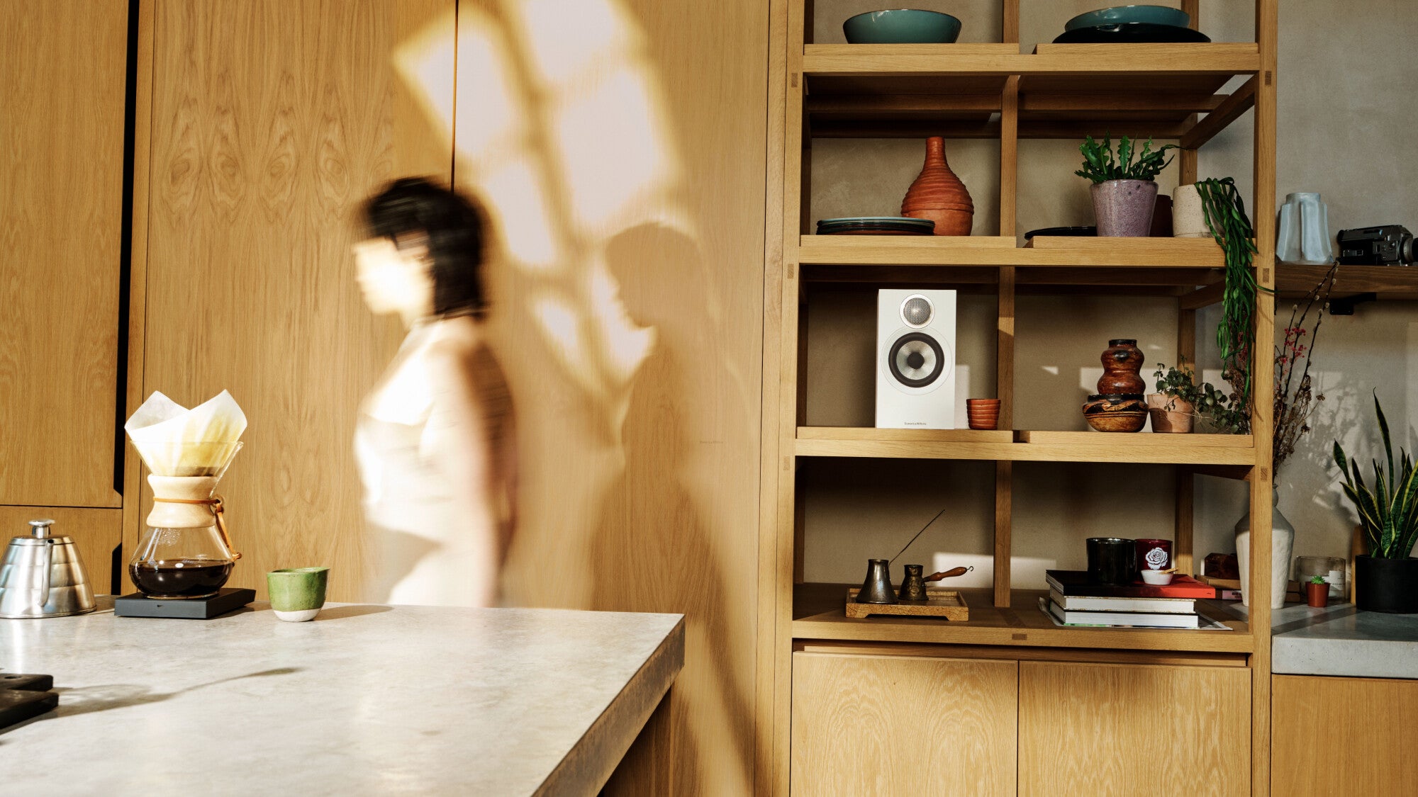B&W 607 S3 Bookshelf Speaker in a modern kitchen and a person passing through