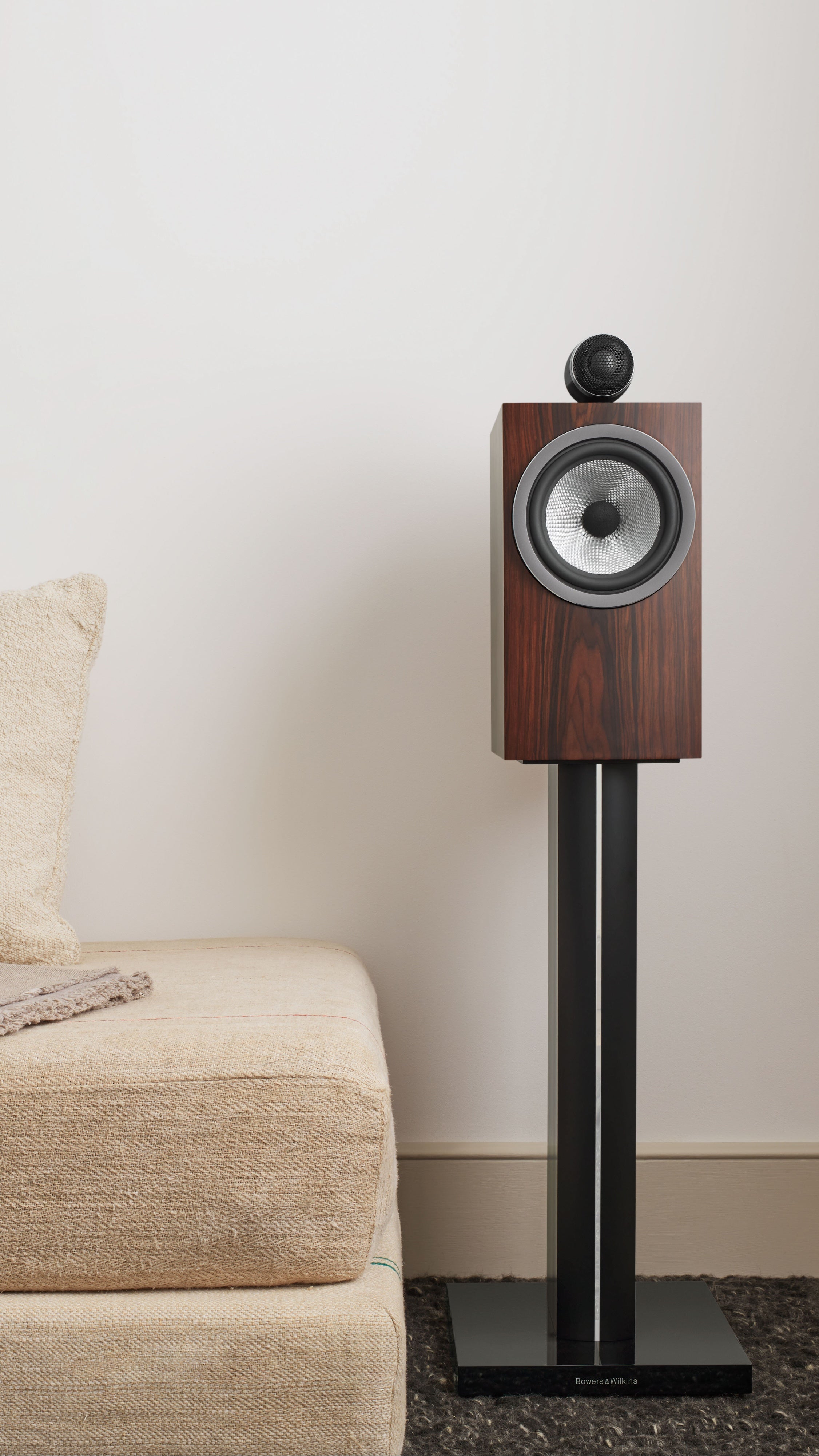 A B&W 705 S3 Bookshelf Speaker standing in a modern living room next to a couch.