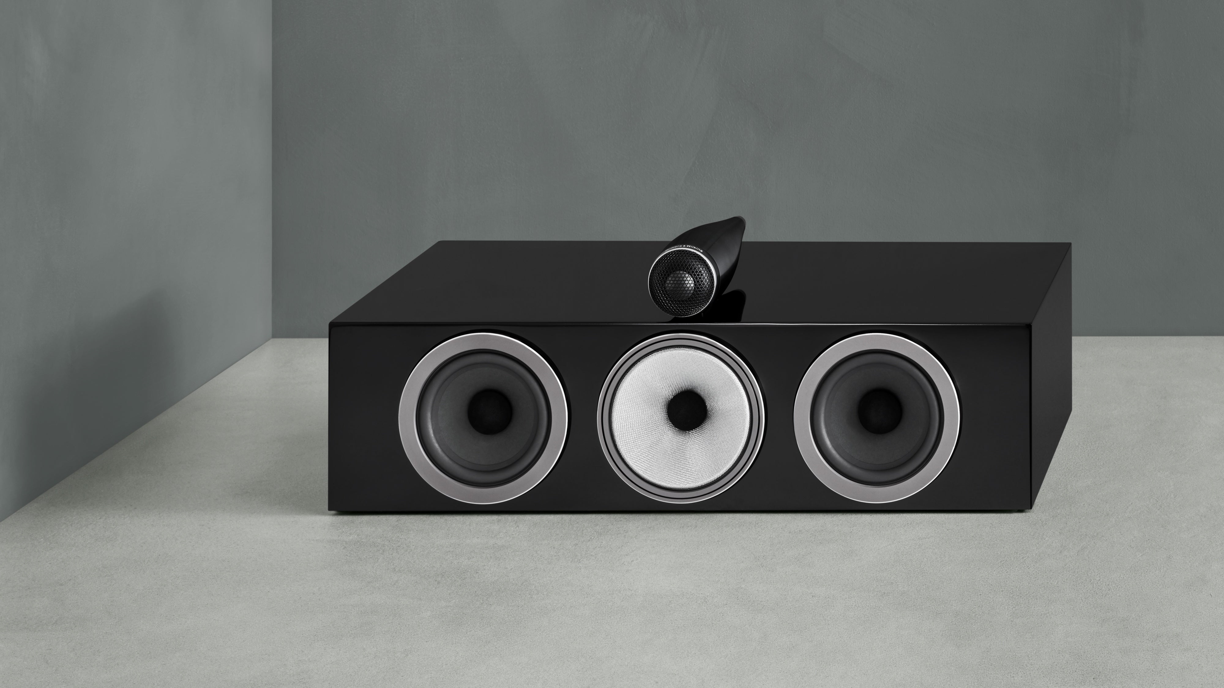 A B&W HTM71 S3 speaker in black finish on a ground.