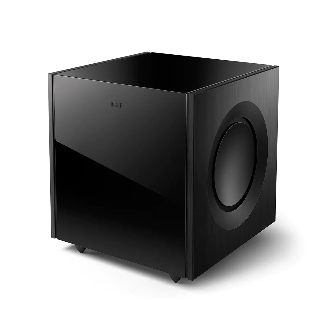A black KEF Reference 8b subwoofer with a front-firing speaker and a large volume knob on the front.