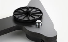 Black Rega turntable platter and tonearm on a sculpted charcoal plinth, designed for home audio systems.