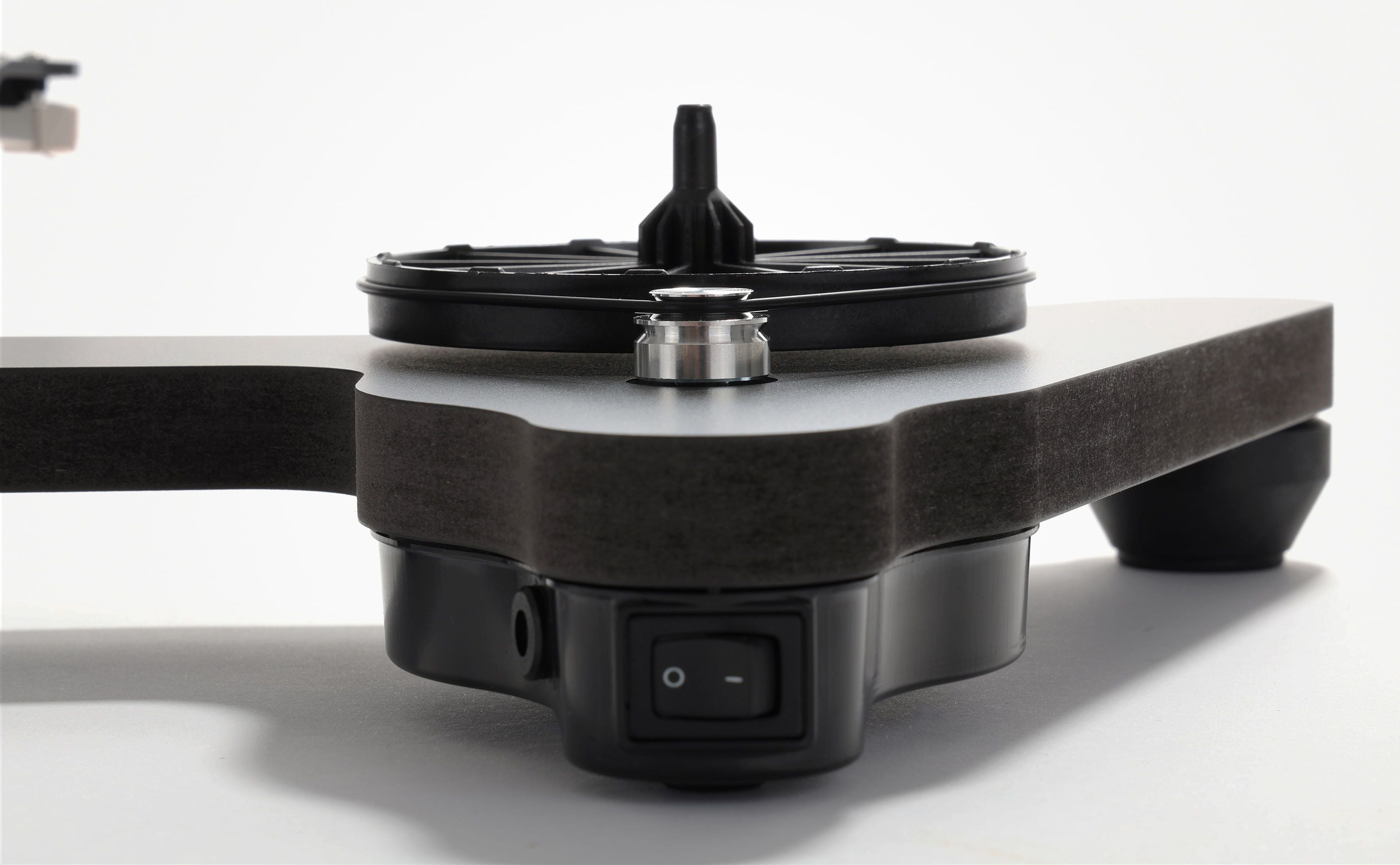 Black Rega turntable with a dark wood plinth, circular platter, tonearm, and front power switch.
