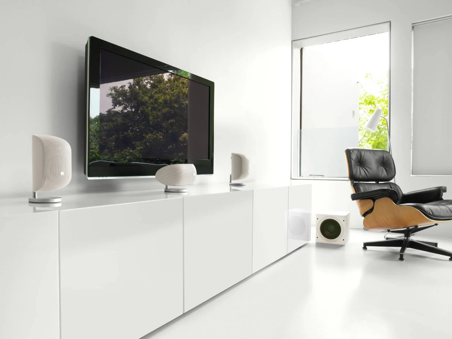 Modern living room with a television mounted on the wall, B&W ASW610 10” Subwoofer, speakers, and a chair.