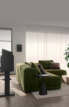 Modern living room with a green sofa, coffee table, and decorative elements and KEF Q8 Meta Atmos Speaker.
