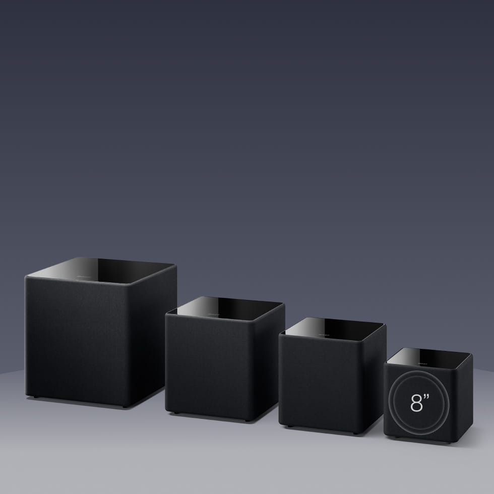Set of four black square KEF KUBE MIE Subwoofers with varying sizes on a gray background