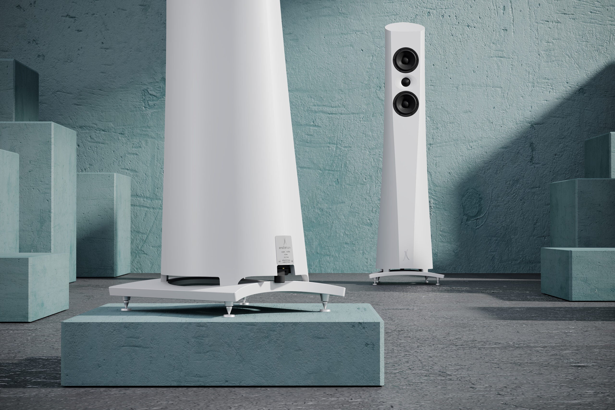 An Estelon white Aura Floor Standing Speaker with a white front and black base, featuring a minimalist design on a modern background.