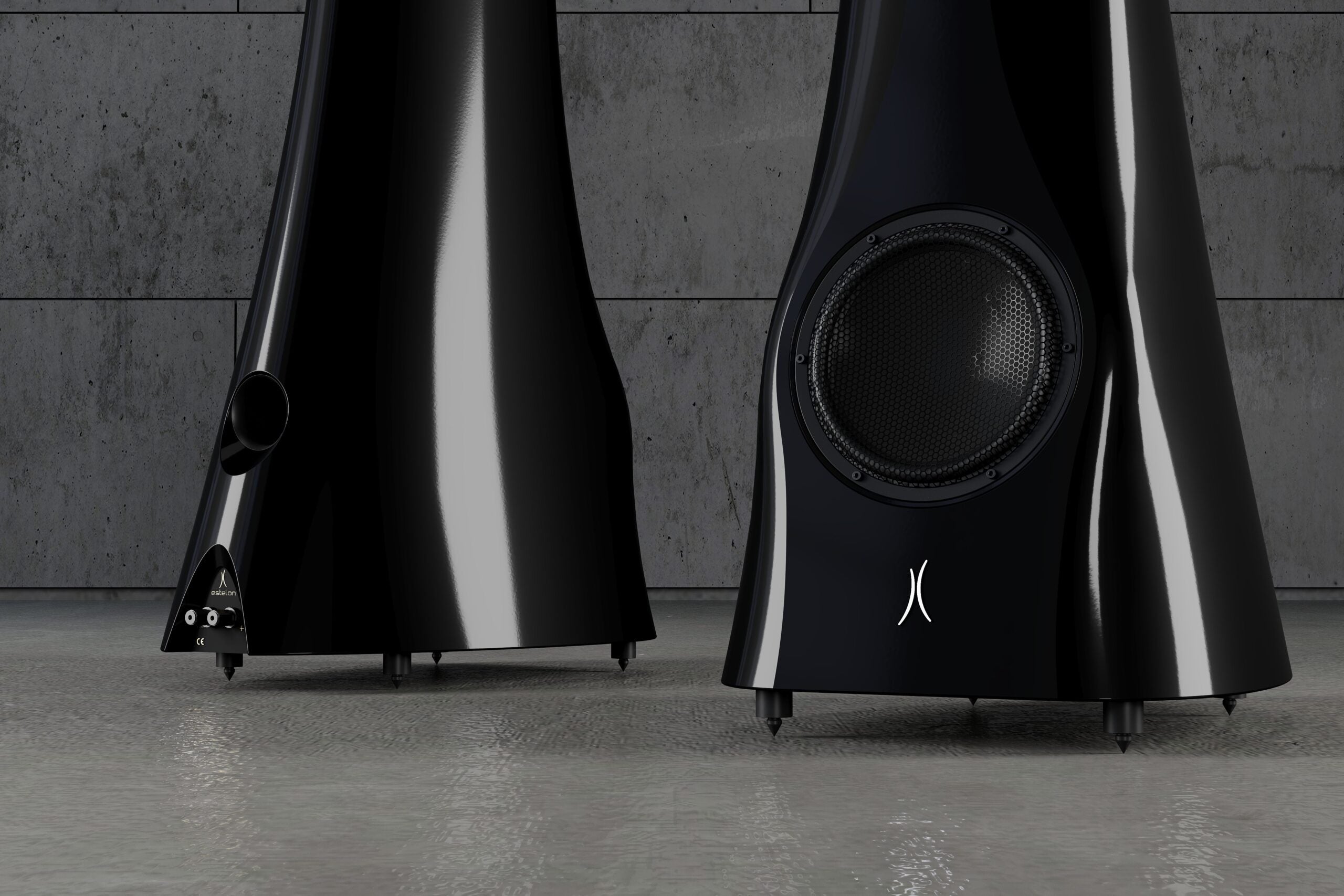 A closeup on a pair of Black Lava Liquid Gloss Estelon XB MK II reference speakers with a curved-sculptural design, standing in an industrial environment.