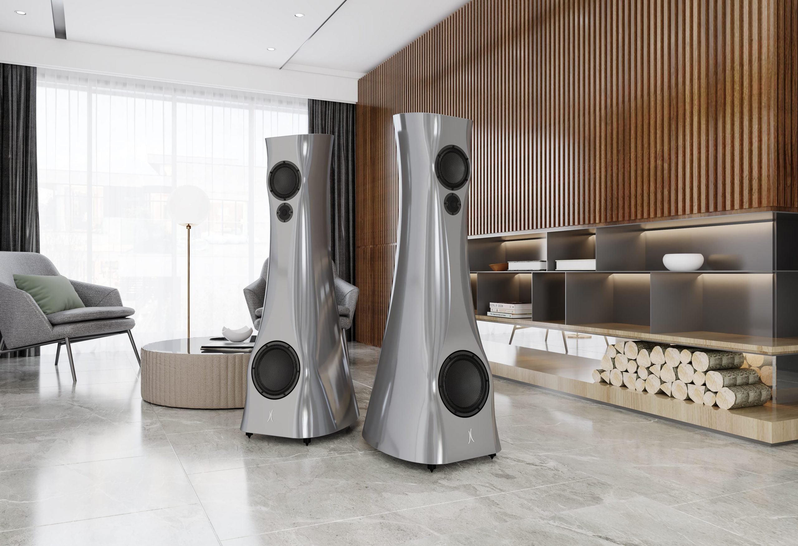 A pair of Silver Pure Alu Liquid Gloss Estelon XB MK II reference speakers with a curved-sculptural design, standing in a modern living room.