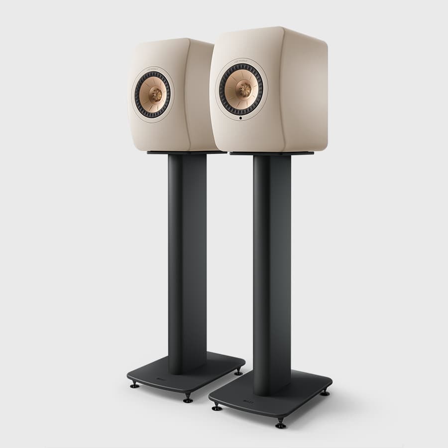 Pair of beige speakers on black KEF S2 Floor Stands for LS Series against a white background