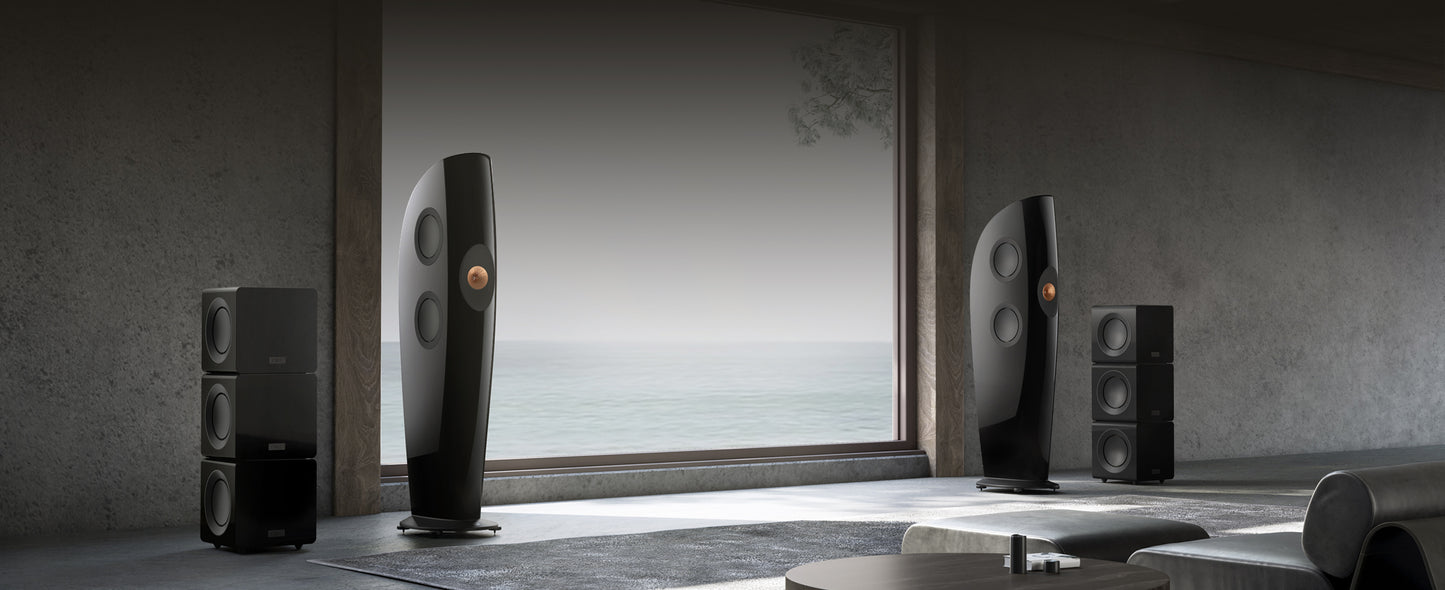 Modern home theater speakers and black KEF KC92 Dual 9” Subwoofers in a room with a large window.