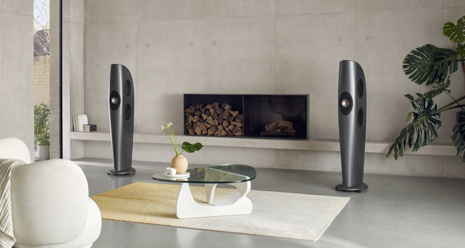 Modern living room with two black KEF Blade One Meta speakers on either side of a television.