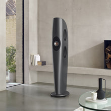 Tall gray KEF Blade One Meta floor-standing speaker in a modern living room setting.