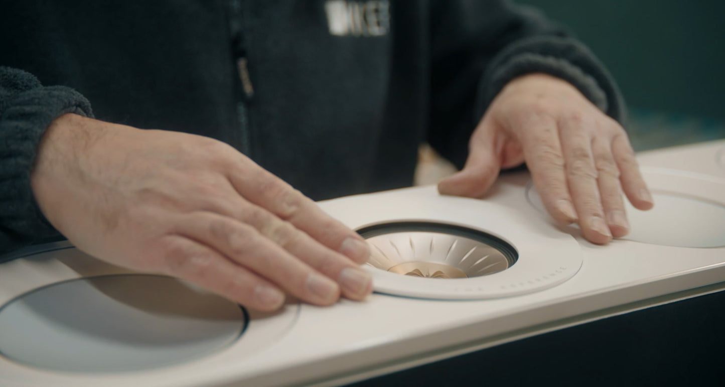 Person inspecting a KEF Reference 2 Meta speaker with their hands on a blurred background