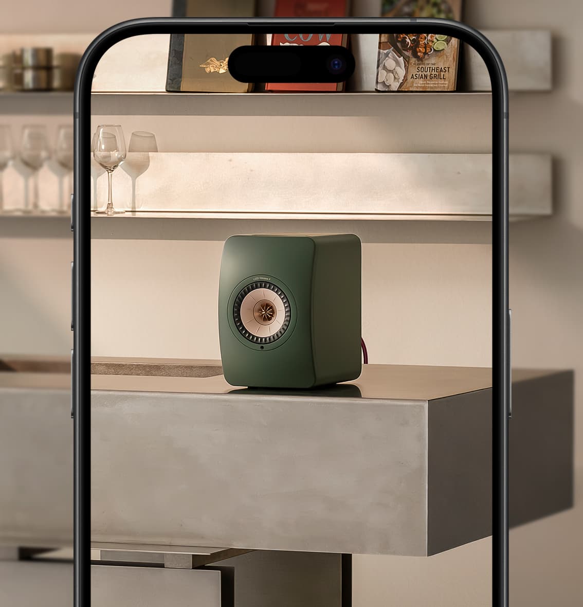 Green moss KEF LS50 II High Resolution Wireless Speaker on a metal shelf with a blurred background