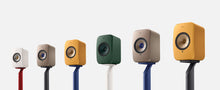 Row of colorful speakers on KEF S1 Floor Stands for LSX II against a white background