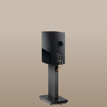 Back side of a black KEF speaker on a KEF S3 Floor Stand for R3 against a beige background