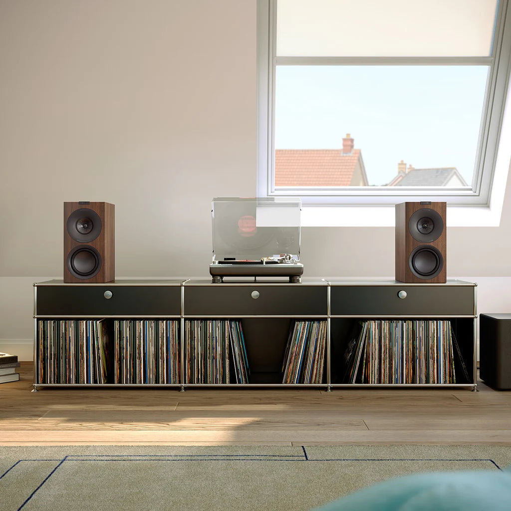 Music setup with KEF Q Concerto Meta Bookshelf Speakers in walnut finish, record player, and vinyl records on a console in a room.