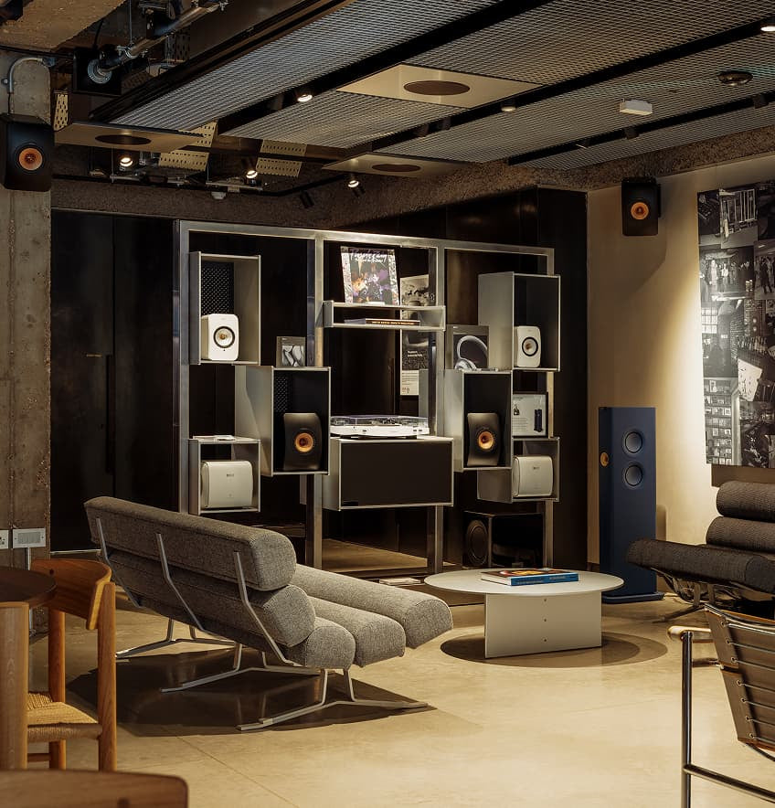 Modern living room with audio equipment and concrete walls and mineral white KEF LS50META Bookshellf Monitors.