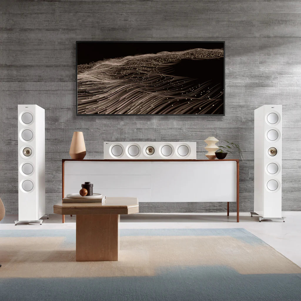 Modern living room with white KEF Reference 4 Meta speakers, a console table, and abstract wall art.