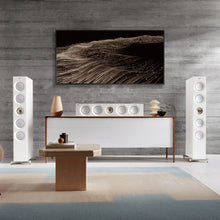 Modern living room with white KEF Reference 4 Meta speakers, a console table, and abstract wall art.