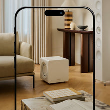 A living room scene with a white KEF KC92 Dual 9” Subwoofer and a wooden table.