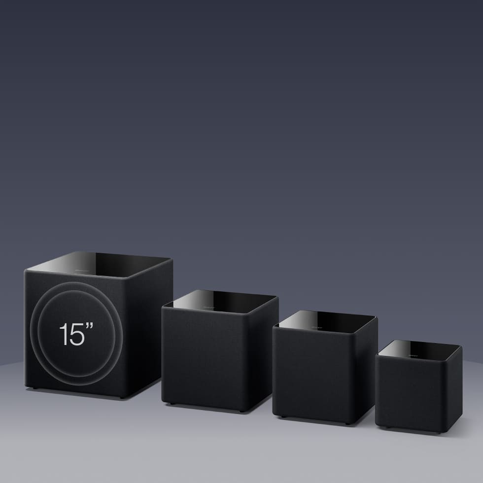 Set of four black KEF KUBE MIE Subwoofers with varying sizes on a gray background